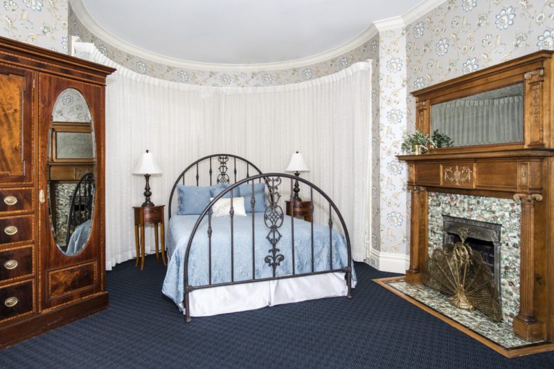 Photo of queen bed with tile-faced decorative fireplace